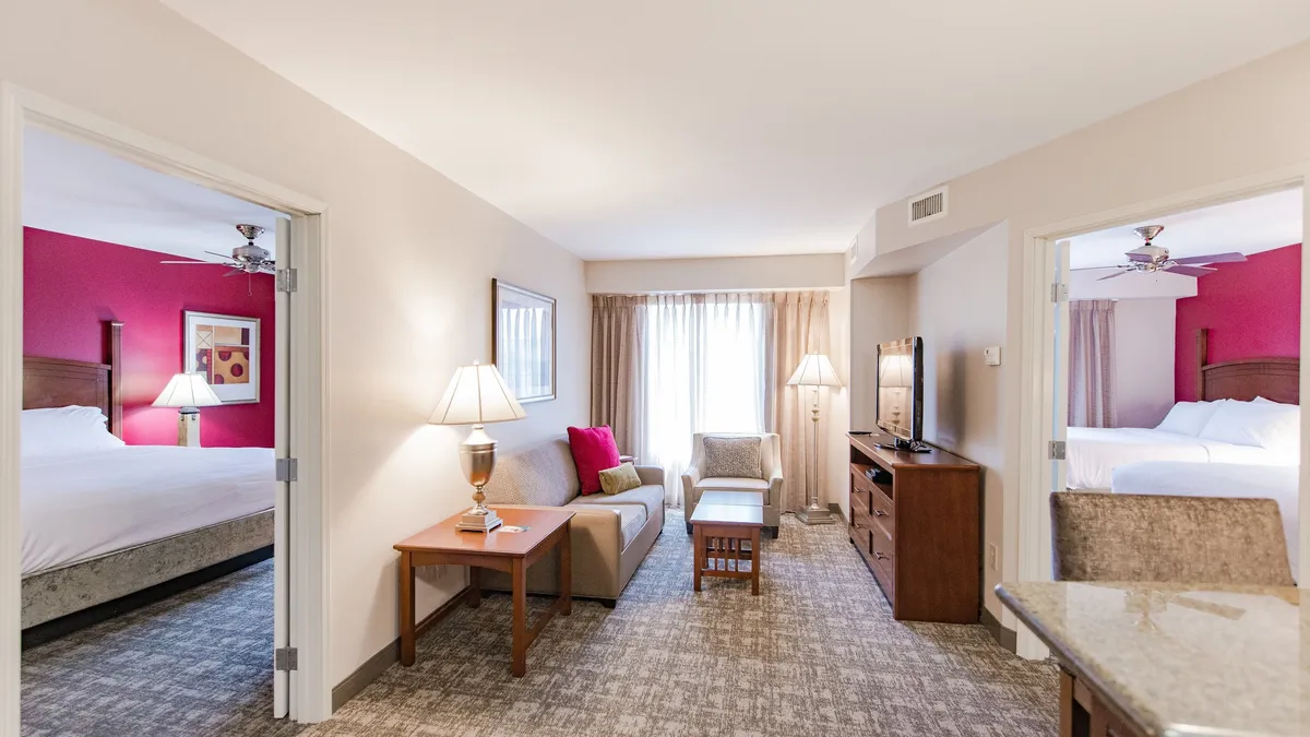 The hero image features a stylish condo living room with a plush sofa, warm lighting from contemporary lamps, a large TV, and inviting bedroom doors in view—creating a welcoming and comfortable gathering space.
